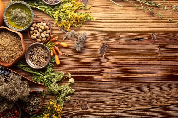 Natural medicine background. Assorted dry herbs in bowls, mortar and plants on rustic wooden table.