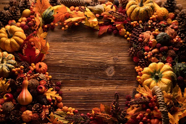 Autumn composition on a rustic wooden background. Decorative pumpkins, various leaves, pine cones, nuts. Orange, yellow, red  and brown aesthetics.