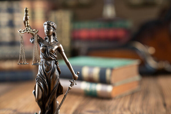 Юридическая тема - должность судьи. Темис скульптура и юридические книги на столе судьи. 