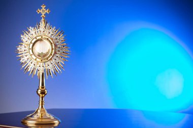 Katolik dini kavramı. Katolik sembolleri kompozisyonu. Haç, Monstrance, Kutsal İncil ve altın kadeh ahşap sunak ve mavi bokeh arka plan. 