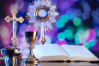 Katolik dini kavramı. Katolik sembolleri kompozisyonu. Haç, Monstrance, Kutsal İncil ve altın kadeh ahşap sunak ve mavi bokeh arka plan. 
