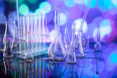 Covid 'e karşı test ve ilaç ile ilgili laboratuvar araştırmaları. Mavi bokeh arka planda cam tüpler ve beherler.