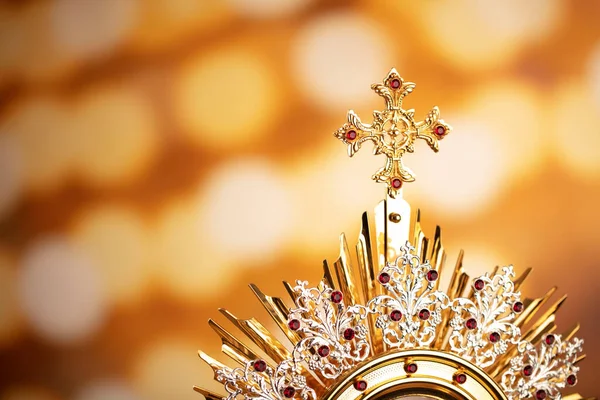 Catholic religion concept. Catholic symbols composition. The monstrance  on yellow bokeh background.