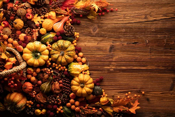 Autumn composition on a rustic wooden background. Decorative pumpkins, various leaves, pine cones, nuts. Orange, yellow, red  and brown aesthetics.