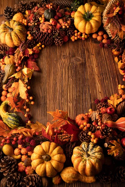 Autumn composition on a rustic wooden background. Decorative pumpkins, various leaves, pine cones, nuts. Orange, yellow, red  and brown aesthetics.