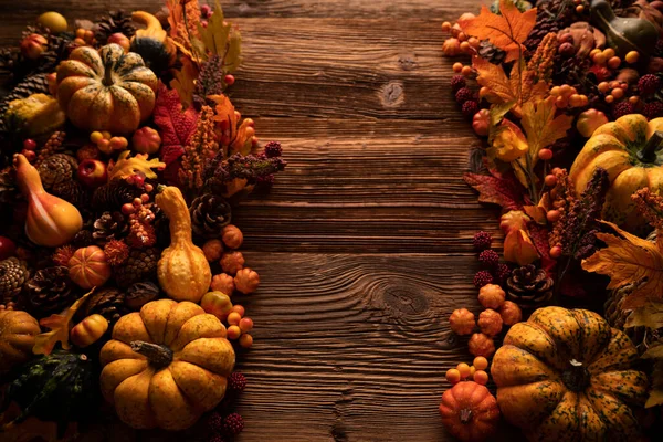 Autumn composition on a rustic wooden background. Decorative pumpkins, various leaves, pine cones, nuts. Orange, yellow, red  and brown aesthetics.