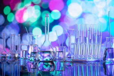 Covid 'e karşı test ve ilaç ile ilgili laboratuvar araştırmaları. Mavi bokeh arka planda cam tüpler ve beherler.
