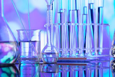 Covid 'e karşı test ve ilaç ile ilgili laboratuvar araştırmaları. Mavi bokeh arka planda cam tüpler ve beherler.