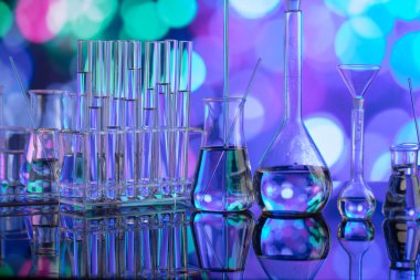 Covid 'e karşı test ve ilaç ile ilgili laboratuvar araştırmaları. Mavi bokeh arka planda cam tüpler ve beherler.