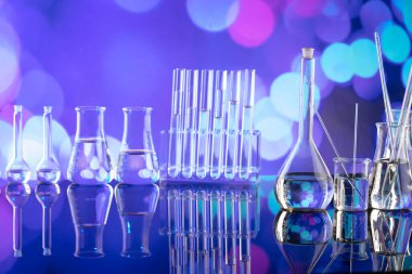 Covid 'e karşı test ve ilaç ile ilgili laboratuvar araştırmaları. Mavi bokeh arka planda cam tüpler ve beherler.