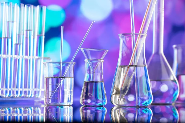 Covid 'e karşı test ve ilaç ile ilgili laboratuvar araştırmaları. Mavi bokeh arka planda cam tüpler ve beherler.