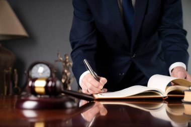 Avukat, hukuk bürosunda belgeleri imzalıyor. Gavel masanın üstünde..