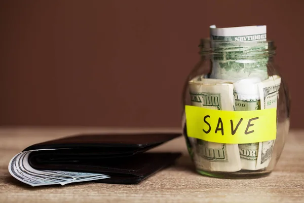 Dollarbiljetten in glazen pot op houten tafel — Stockfoto