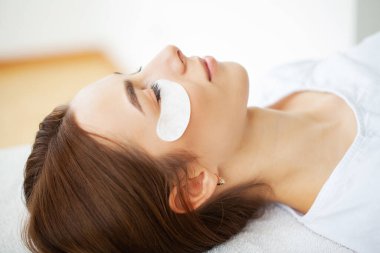 Kirpik uzatma ustası güzel bir kadına kirpiklerini uzatır.