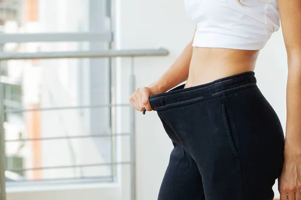 Femme en pantalon oversize après la perte de poids, concept de régime. — Photo