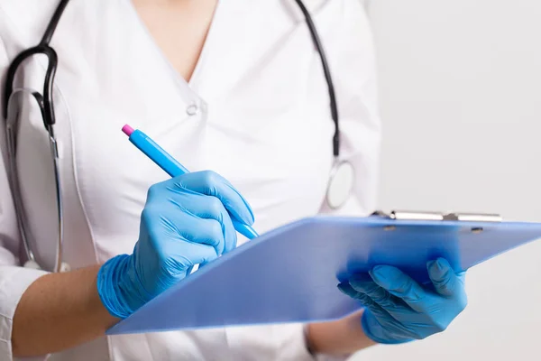 O médico anota a história médica do paciente com caneta no cartão — Fotografia de Stock