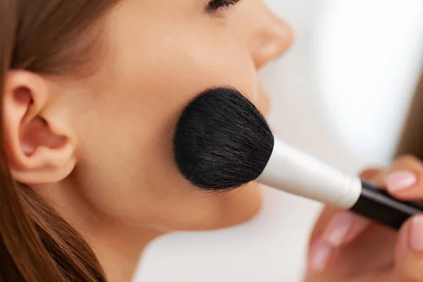 Joven hermosa mujer haciendo maquillaje cerca del espejo — Foto de Stock