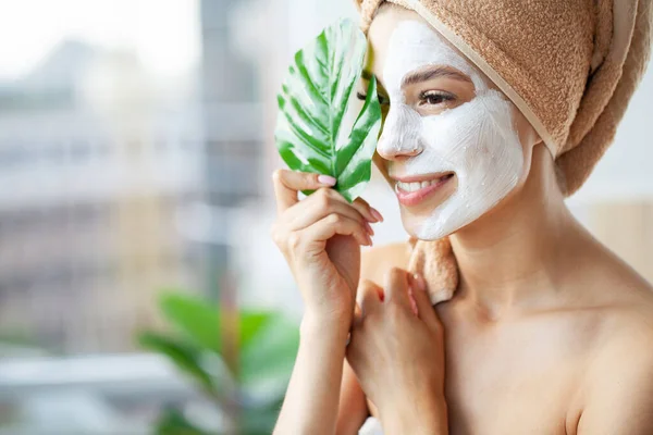 Mulher bonita aplicando máscara facial em seu rosto. — Fotografia de Stock