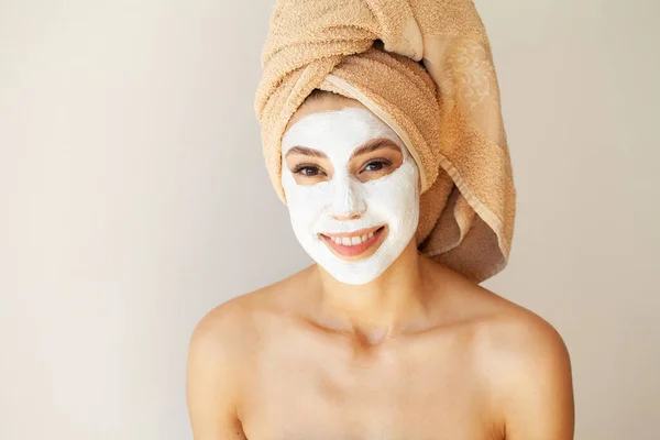 Vacker ung kvinna applicera ansiktsmask på hennes ansikte. — Stockfoto
