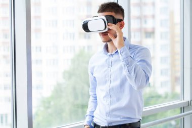 Modern iç tasarım ortak çalışma stüdyosunda sanal gerçeklik gözlüğü takan genç bir adam..