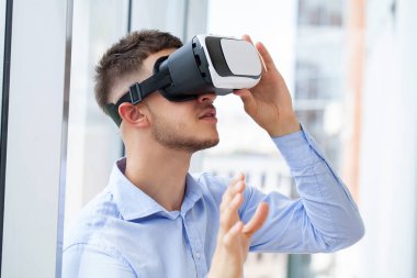 Sanal gerçeklikteki nesnelere dokunmaya çalışan VR kulaklıklı adam
