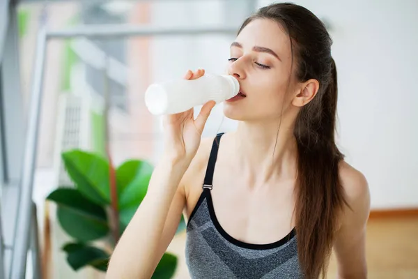 Молодая красивая женщина пьет из пластиковой бутылки йогурта — стоковое фото