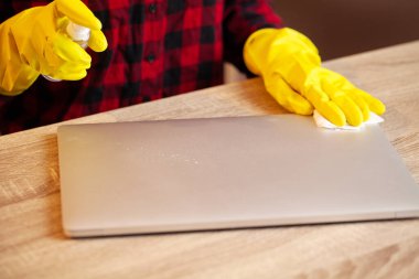Young worker cleaning table with rag in office