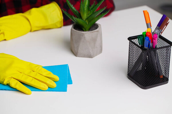 Professional cleaning lady cleans table using a sponge and spray
