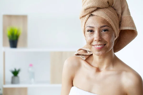 Primer plano de la mujer sonriente aplicando exfoliante de café en la cara — Foto de Stock