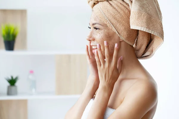 Close up of smiling woman applying coffee scrub on face — Zdjęcie stockowe