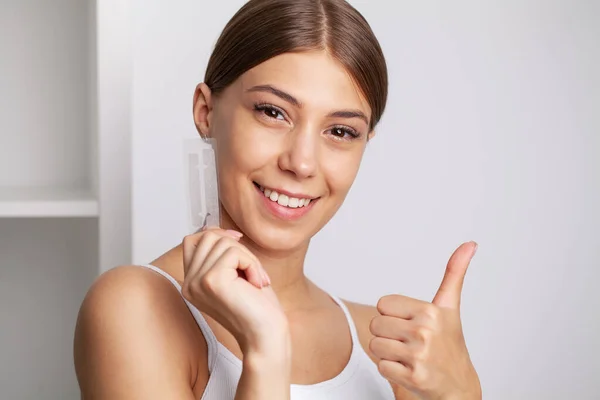 Tandblekning, vacker leende kvinna som håller en blekning remsa — Stockfoto