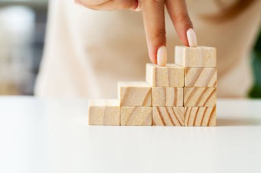 Womens hand folds wooden cubes forming up stairs