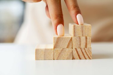 Womens hand folds wooden cubes forming up stairs