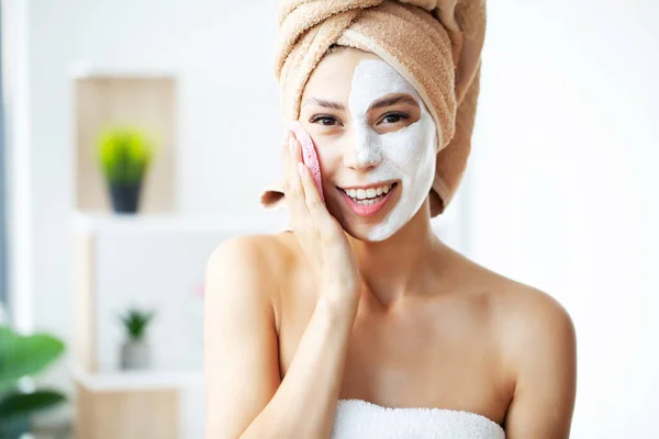Beautiful young woman is getting facial clay mask at spa — Fotografia de Stock