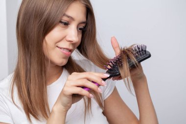 Çekici, gülümseyen bir kadın uzun düz saçlarını tarıyor.