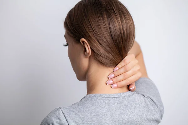 Mujer enferma que sufre de dolor de cuello sobre fondo gris — Foto de Stock