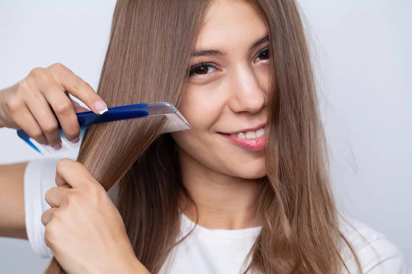 Привлекательная улыбающаяся женщина расчесывает свои длинные прямые волосы — стоковое фото