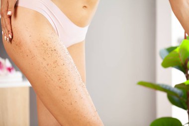 Güzel genç bir kadın evde bacağını ovuyor.