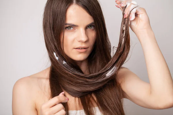 Mulher em um fundo branco com um pente para o cabelo, o problema do cabelo — Fotografia de Stock