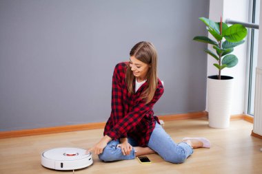 Kadın akıllı robot elektrik süpürgesini açıyor.