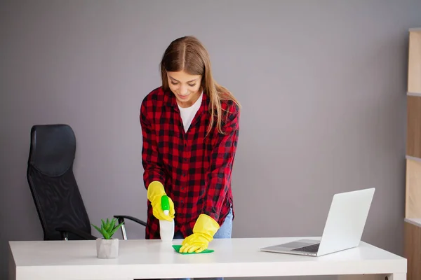 Młody pracownik sprzątanie biurko z szmatą w biurze — Zdjęcie stockowe
