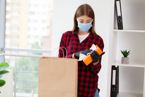 Женщина стирает товары, купленные в супермаркете, дезинфицирующим средством..