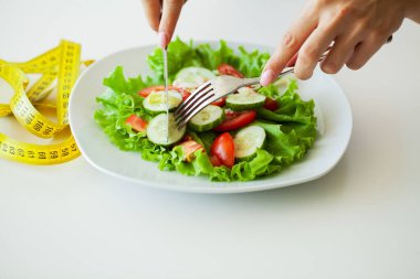 Kadın hamburgerle taze salata arasında seçim yapıyor.