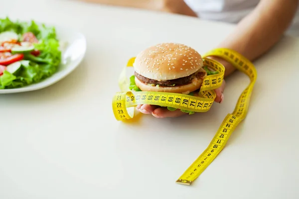 Kvinna väljer mellan skräpburgare och färsk sallad — Stockfoto