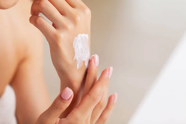 Mujer joven aplicando crema natural sobre la piel en casa — Foto de Stock