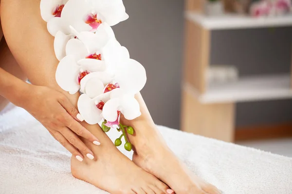Štíhlé dlouhé nohy žena s růžovými květy. — Stock fotografie