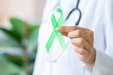 Üniformalı doktor Lyme hastalığının sembolü olarak yeşil bir kurdele tutuyor.