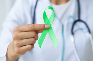 Üniformalı doktor Lyme hastalığının sembolü olarak yeşil bir kurdele tutuyor.