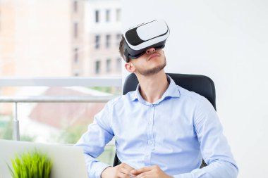 Ofis elbiseli ve sanal gerçeklik gözlüklü bir adam havaya dokunuyor..