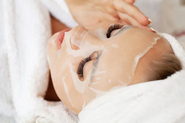 Kosmetolog nanáší masku na ženu v lázeňském salonu — Stock fotografie